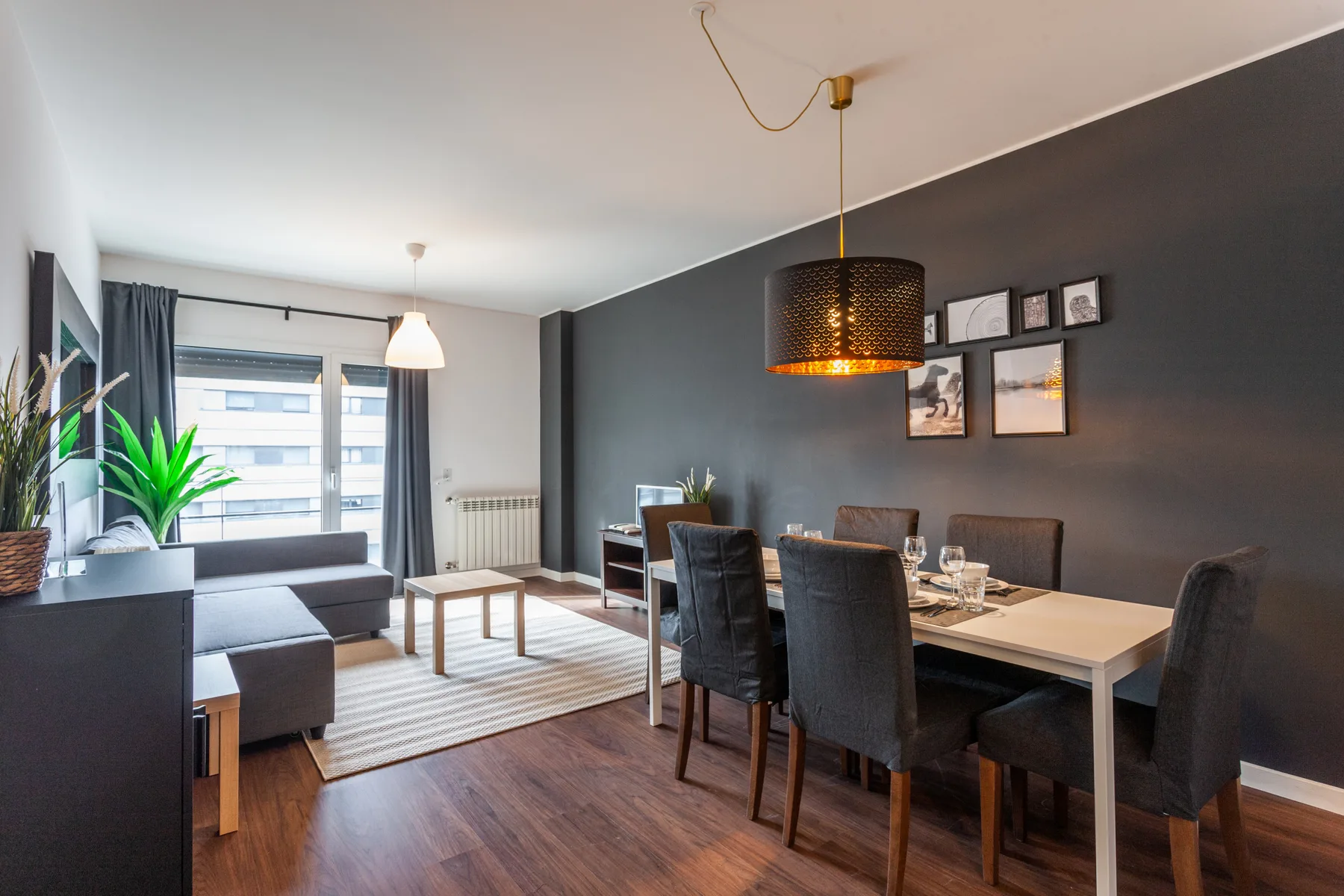 A combined living and dining area with a sofa, table, and dark accent wall.