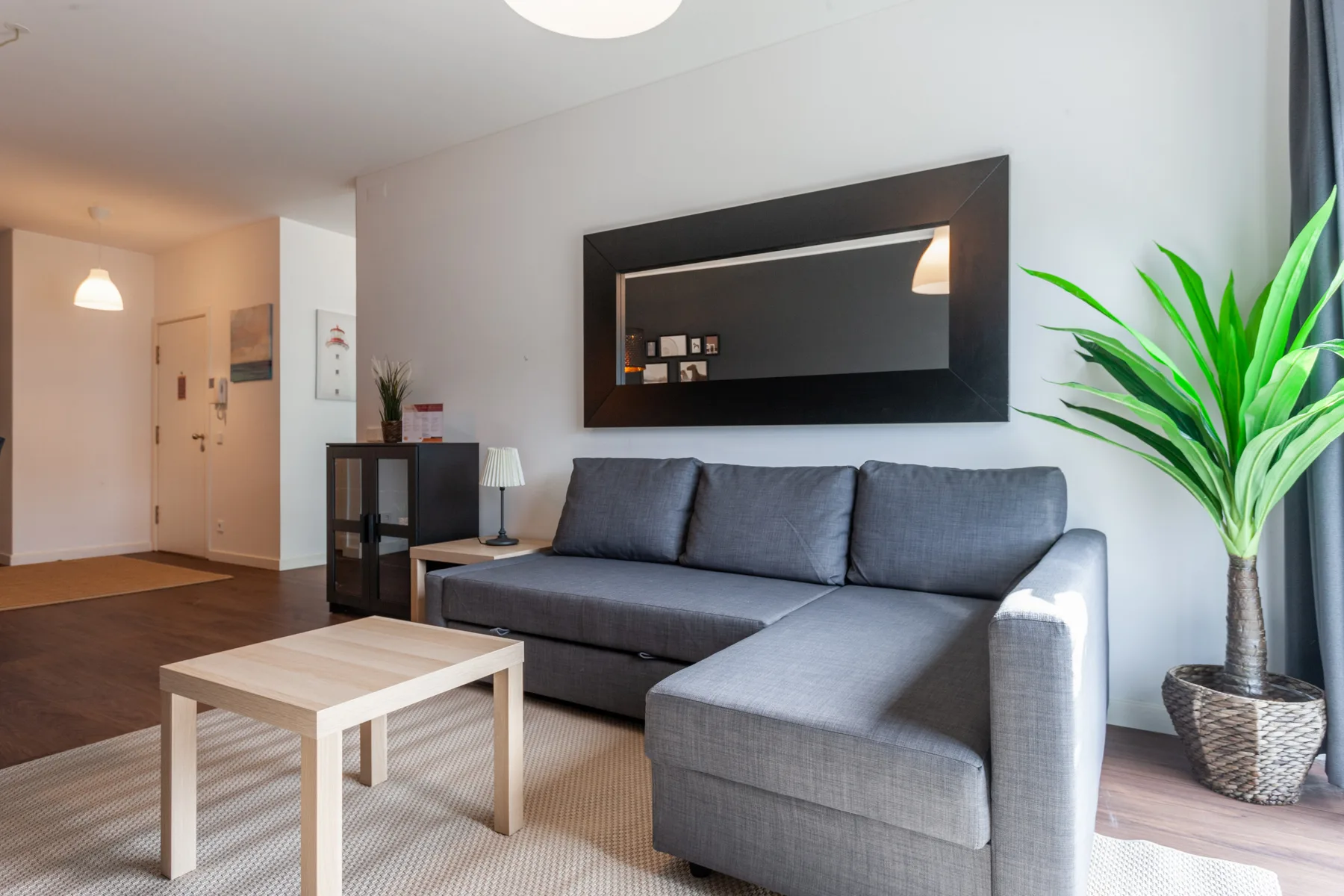 A living room with gray seating, a coffee table, and a large wall mirror.