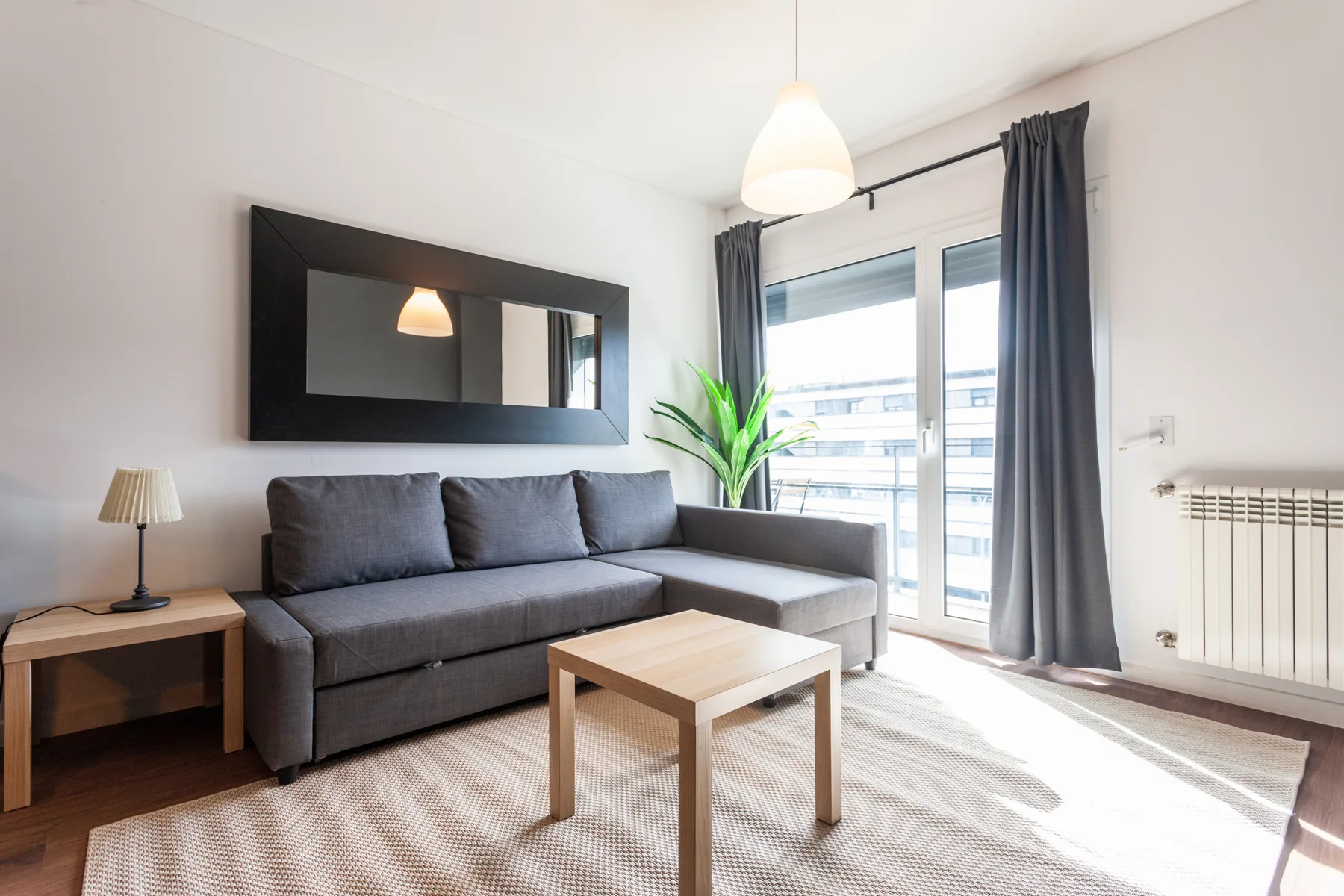 A bright living room with seating, a coffee table, and a large window.
