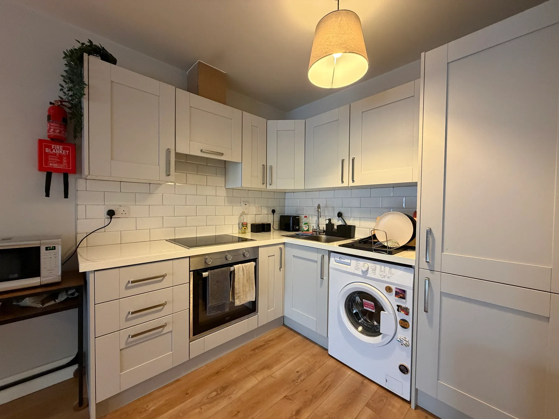 A compact kitchen with white cabinets, a countertop, and a washing machine.