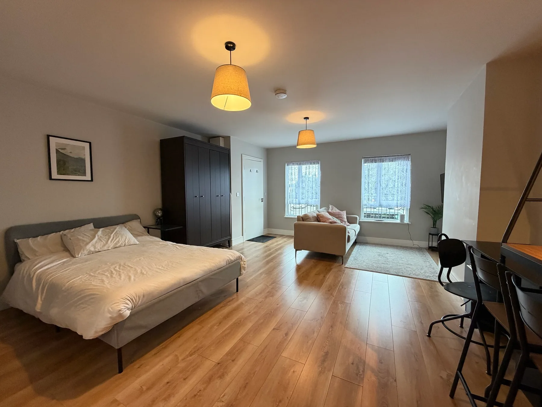 A bedroom and sitting area with a bed, seating, and a desk.