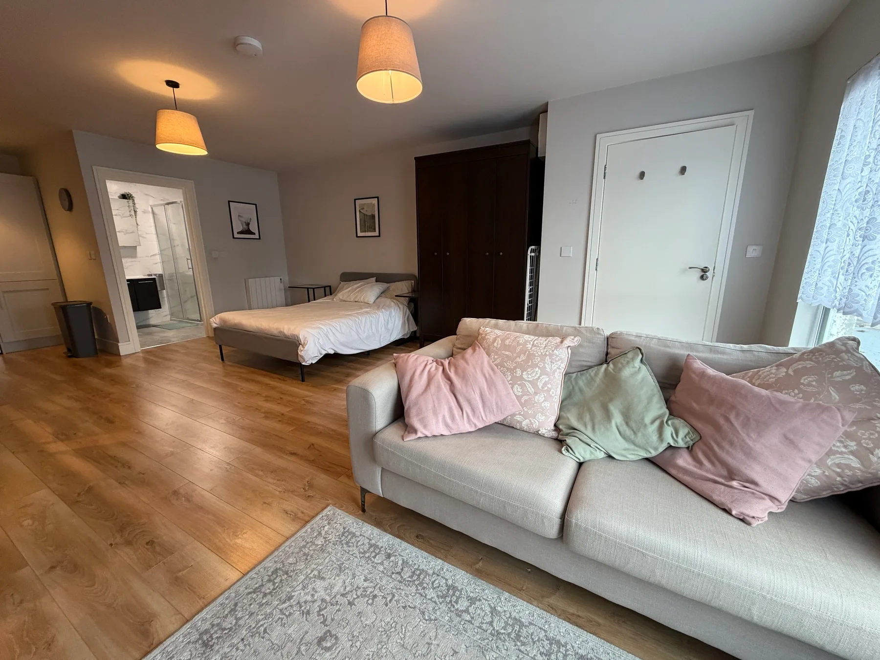 A bedroom with a bed and a seating area beside a large window.