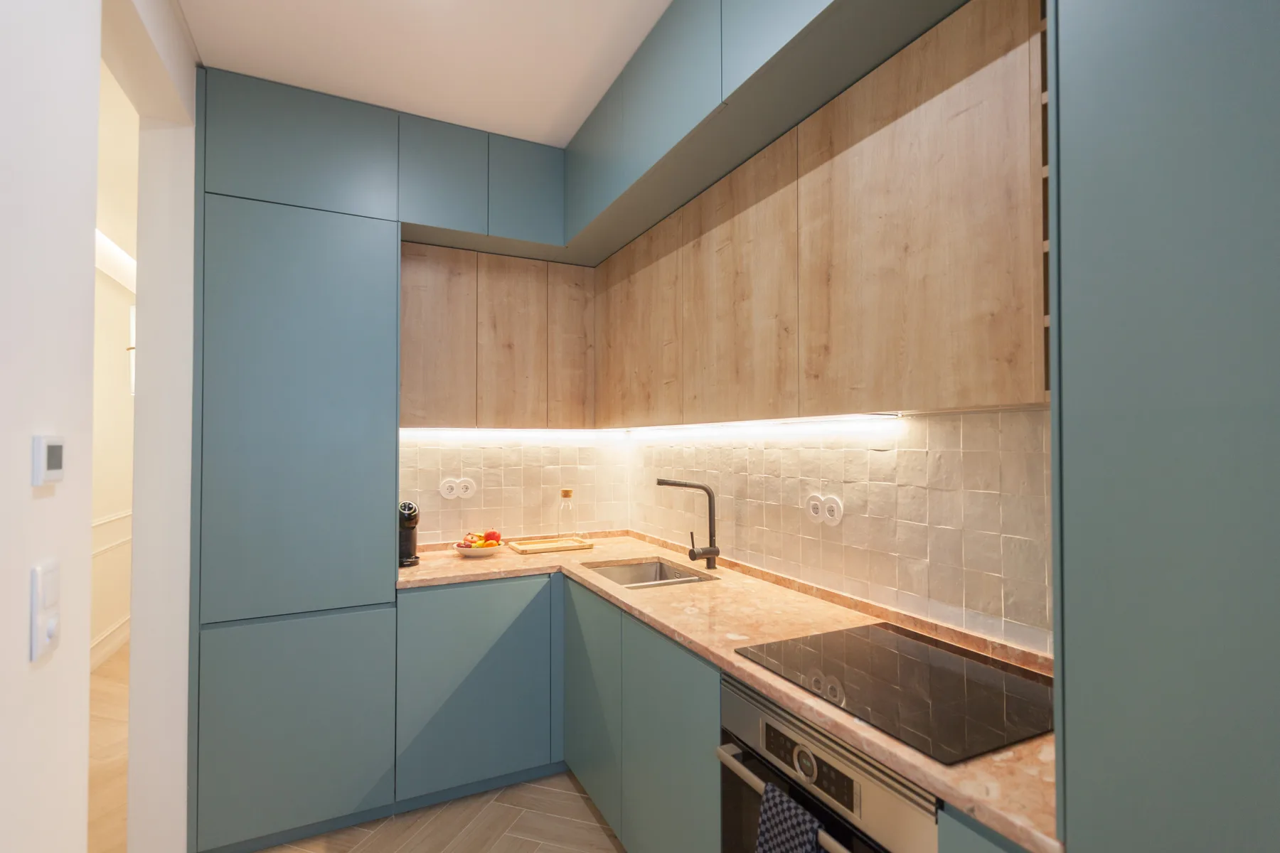 Una cocina compacta con gabinetes azules, armarios en tonos de madera y una placa de cocción.