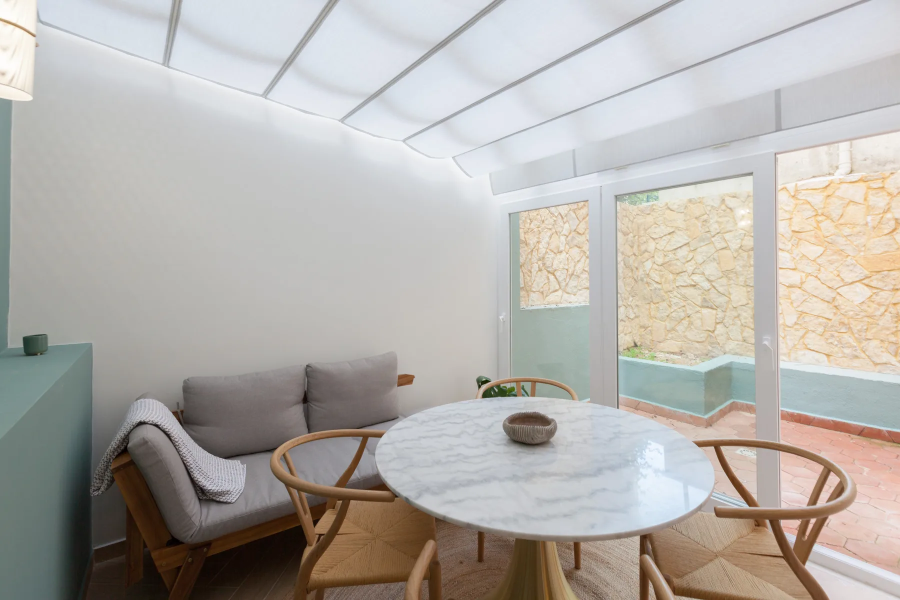 Una luminosa sala de estar con una mesa redonda y puertas de vidrio que dan a un patio.