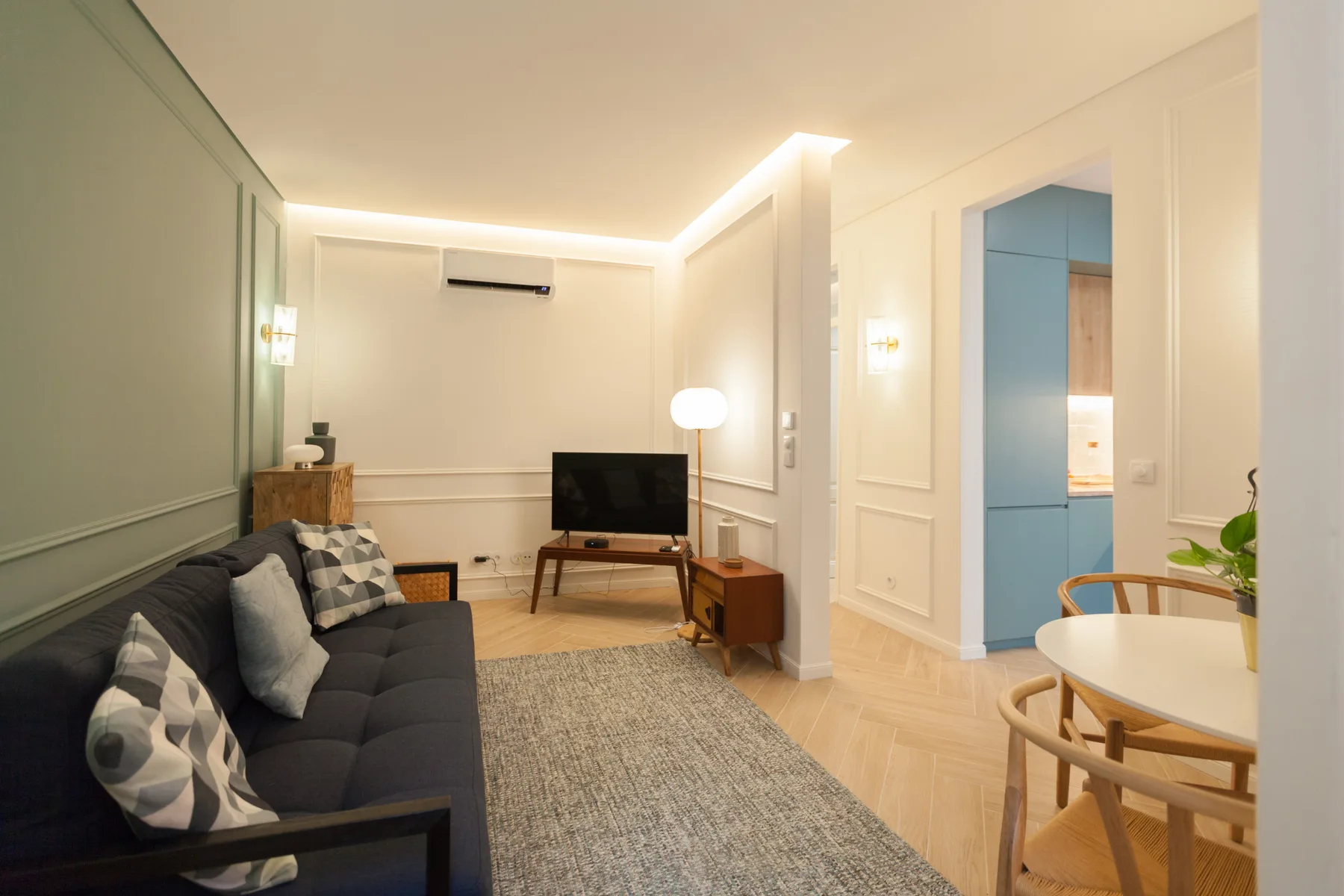 Una sala luminosa con asientos, un televisor y un comedor.