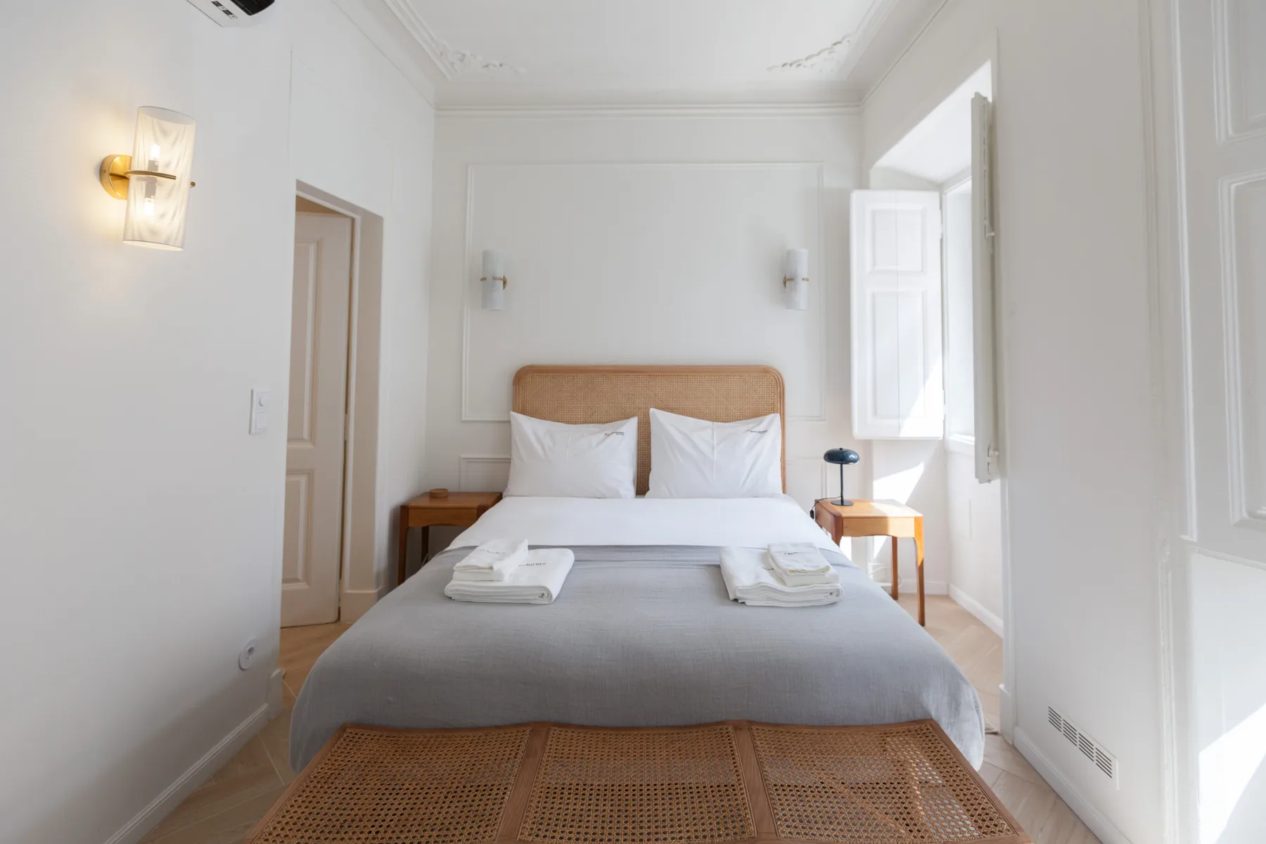Un dormitorio luminoso con una cama bien hecha y una ventana abierta.