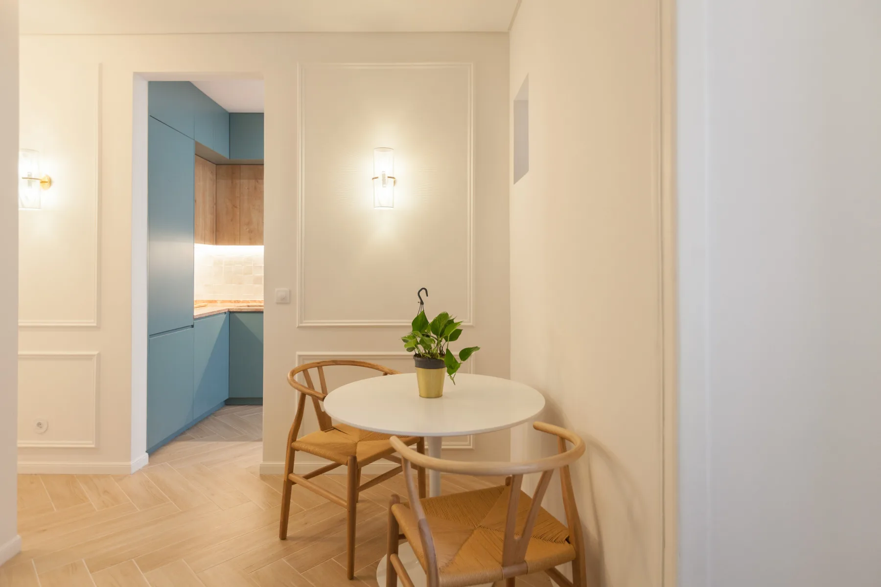 Un comedor con una mesa redonda y sillas junto a una cocina azul.