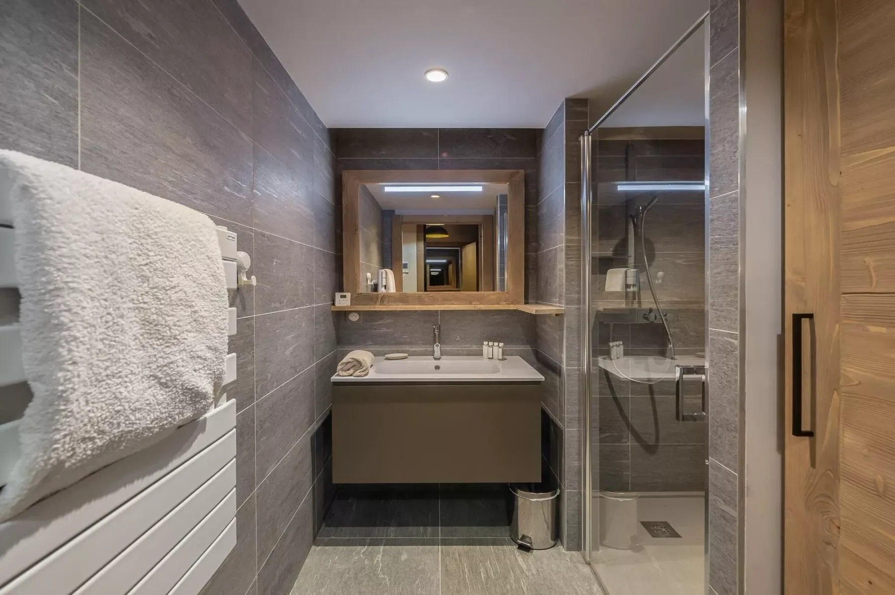 Un baño moderno con tocador, espejo grande y ducha de vidrio.