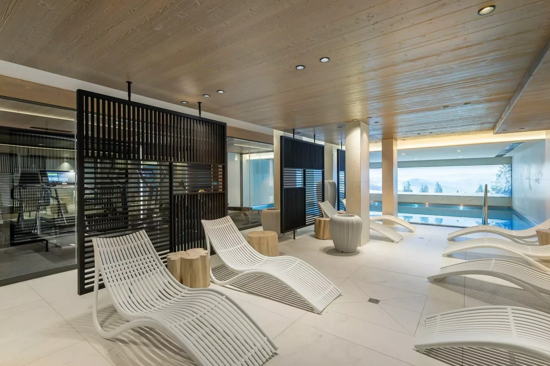 Una sala interior luminosa con asientos curvos y grandes ventanales con vistas al agua.