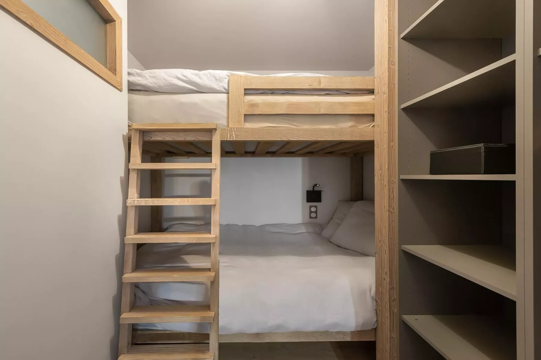 Una zona para dormir compacta con dos camas apiladas y una escalera de madera.
