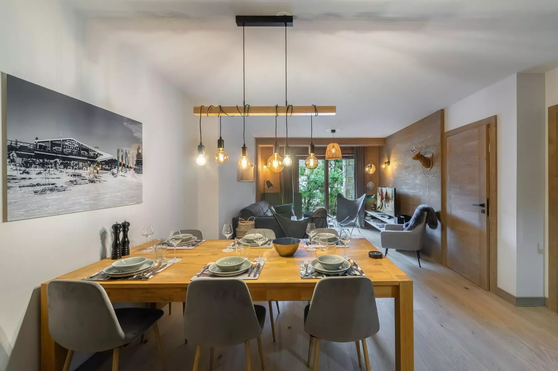 Un comedor con una larga mesa de madera bajo lámparas colgantes.