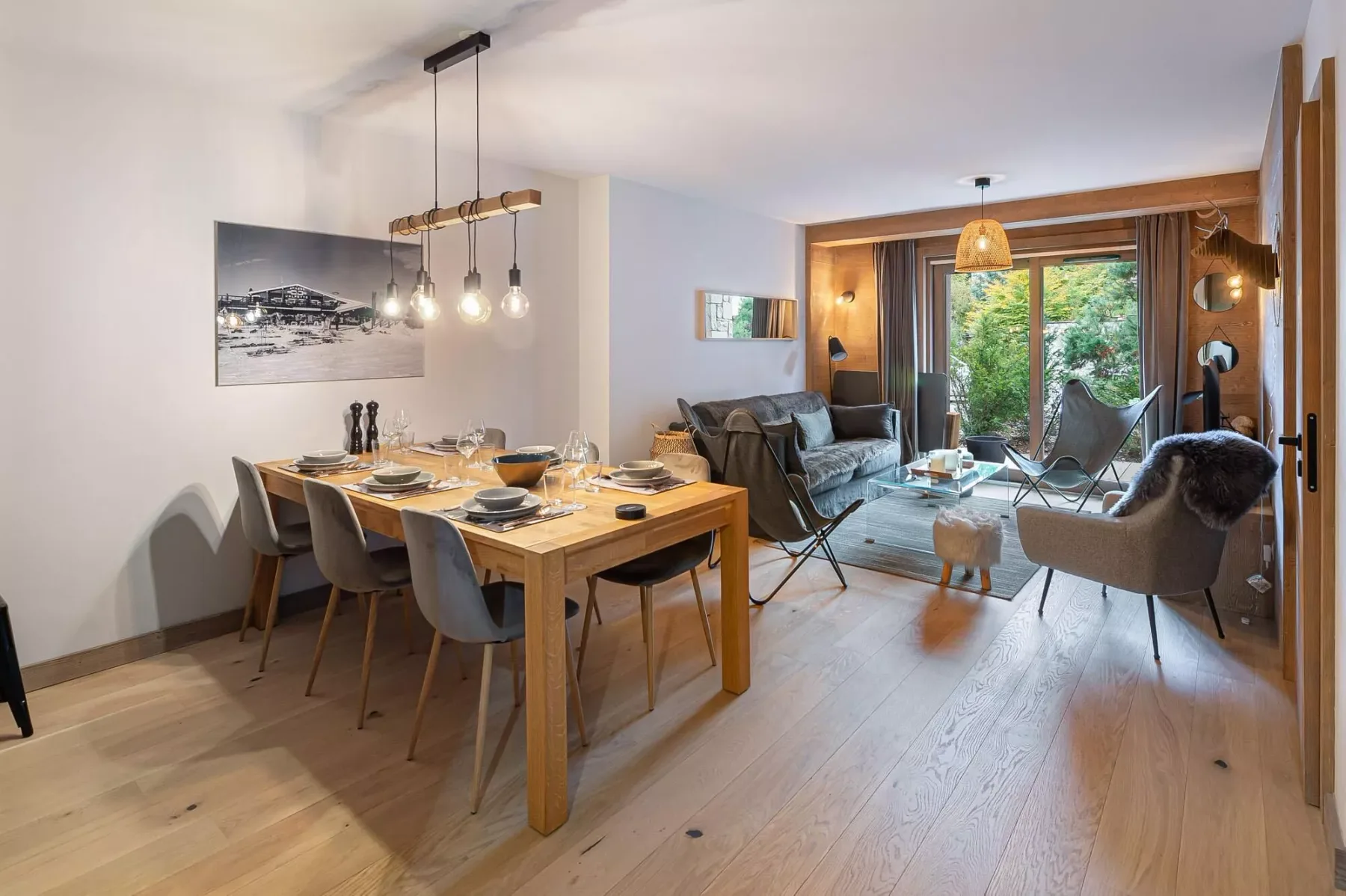 Un salón-comedor diáfano con una mesa de madera y asientos.