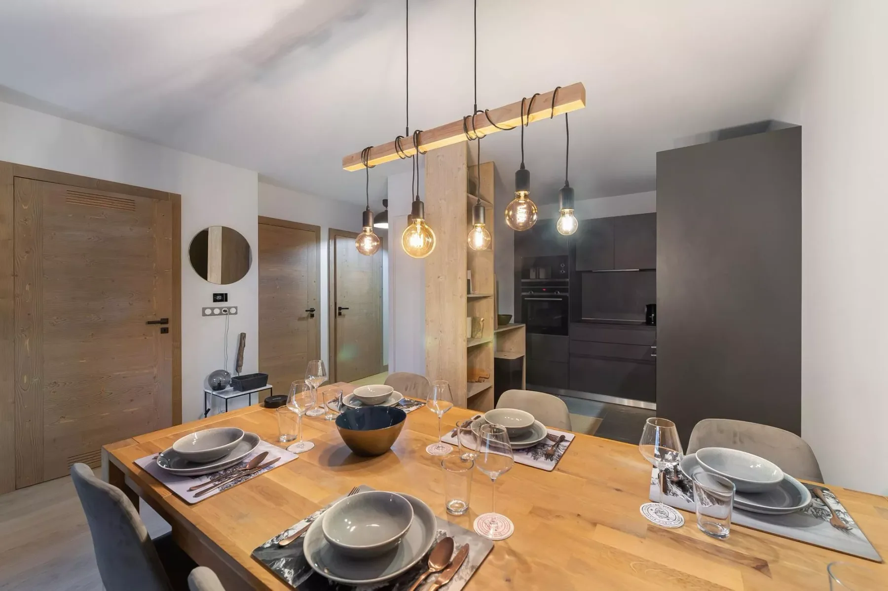 Un comedor con una mesa de madera puesta junto a una cocina moderna.