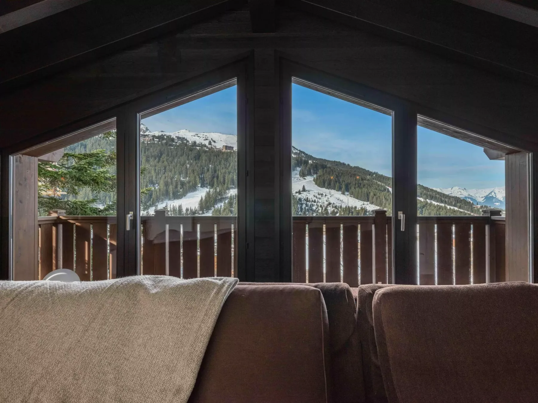 A seating area faces large windows overlooking a snowy mountain landscape.
