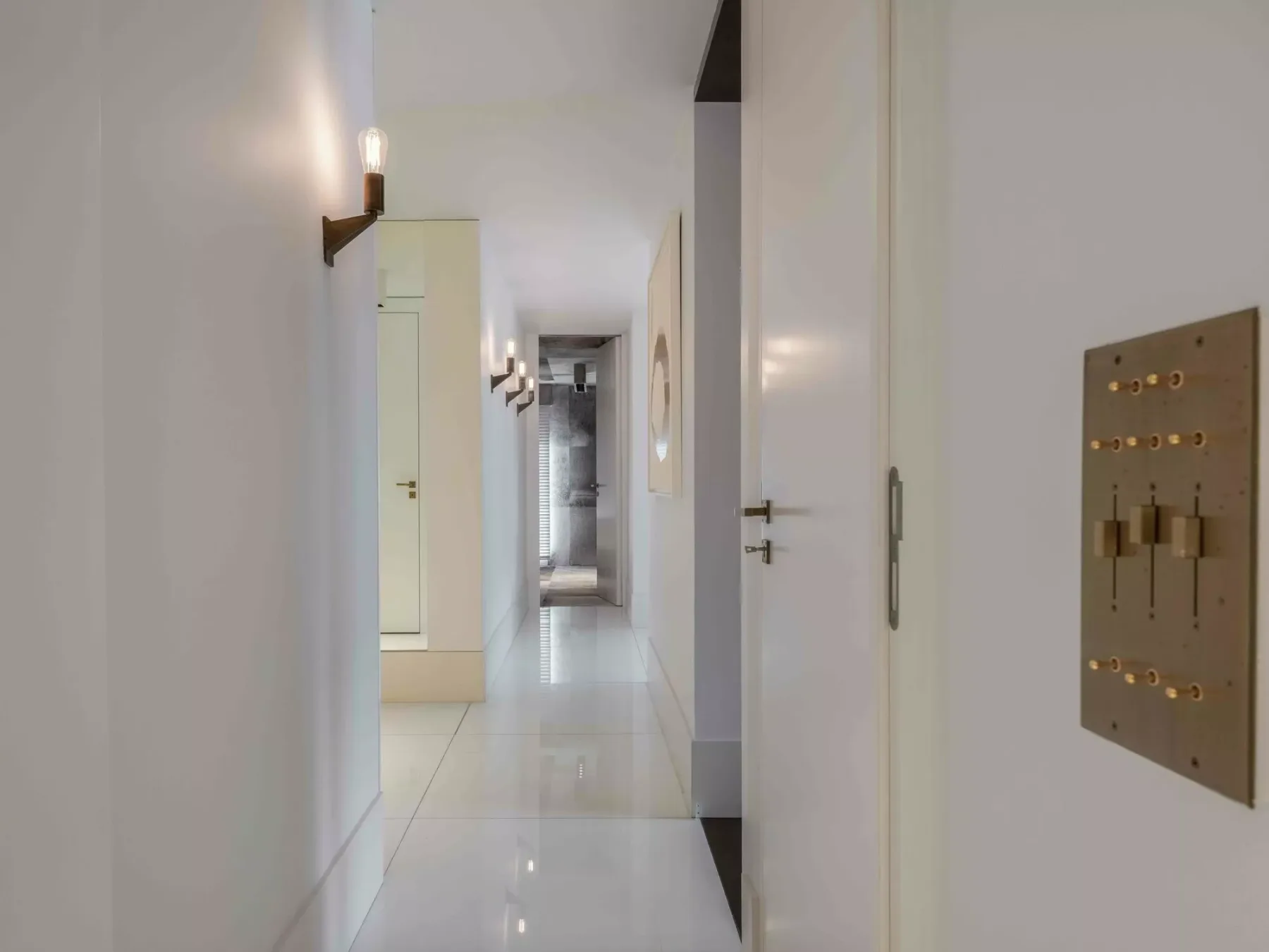 Un pasillo interior luminoso con paredes blancas y suelo de baldosas.