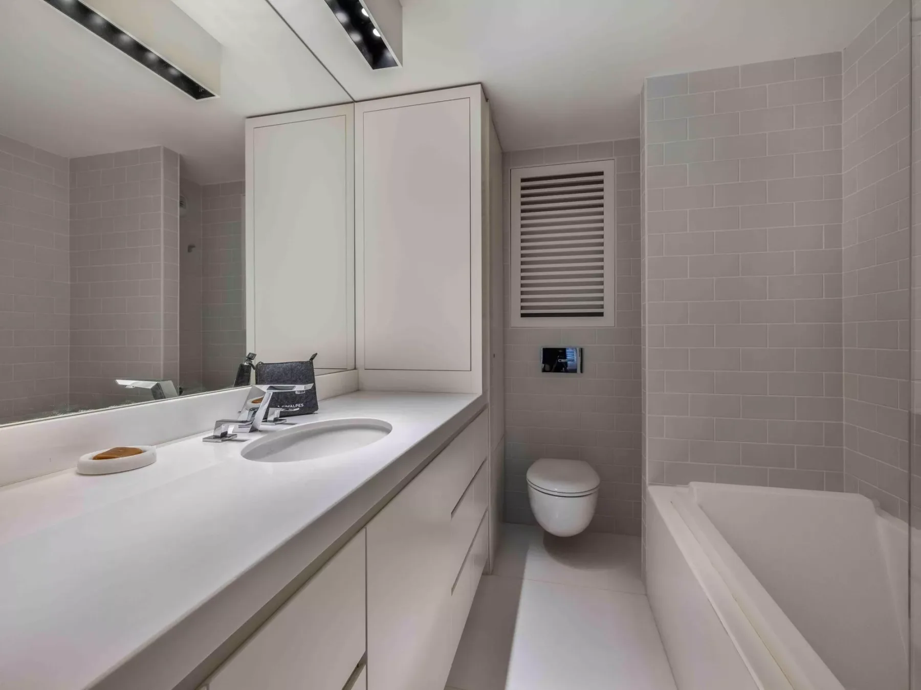 Un baño luminoso con un lavabo amplio y una bañera.