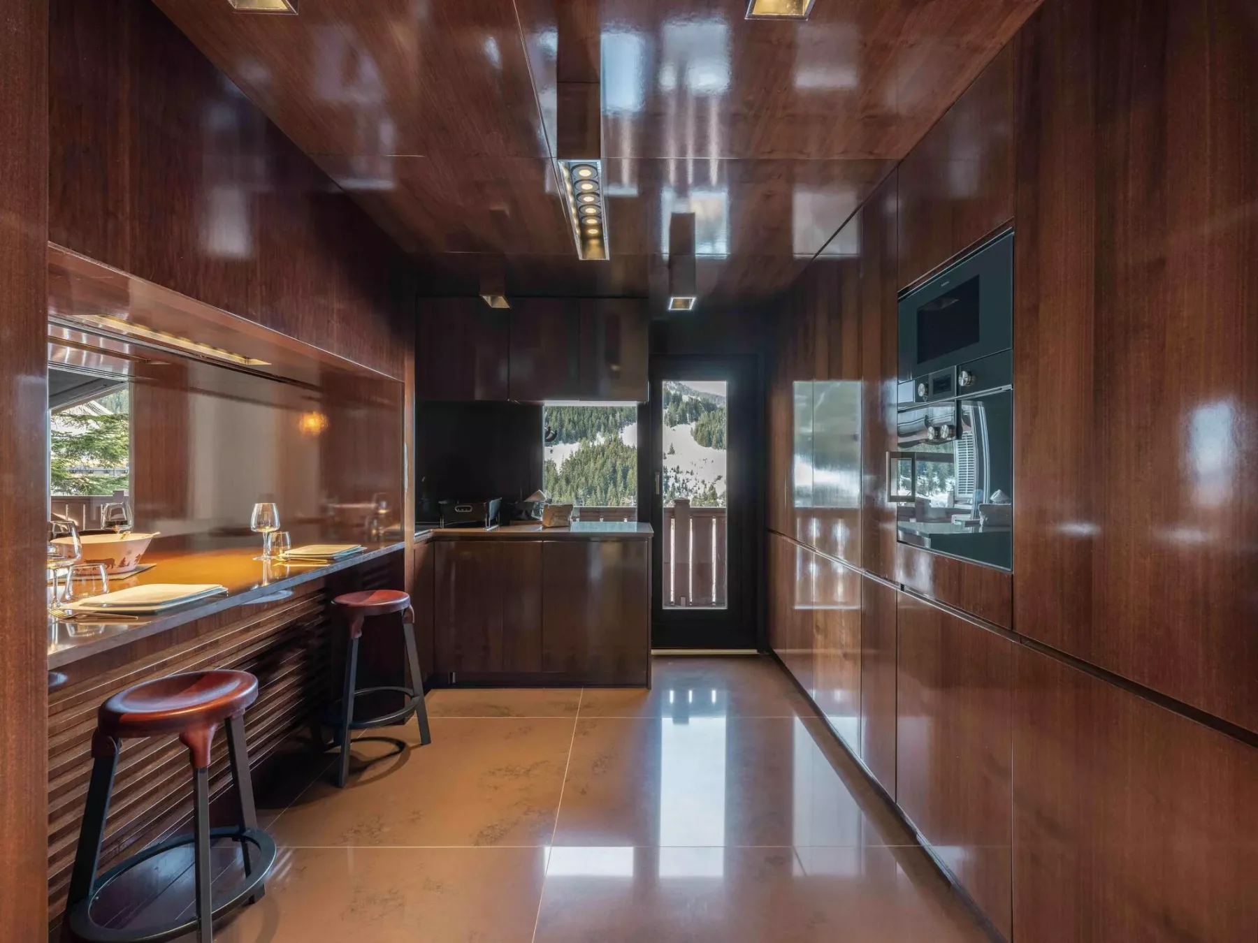 Una cocina compacta con gabinetes de madera oscura, una encimera y electrodomésticos integrados.