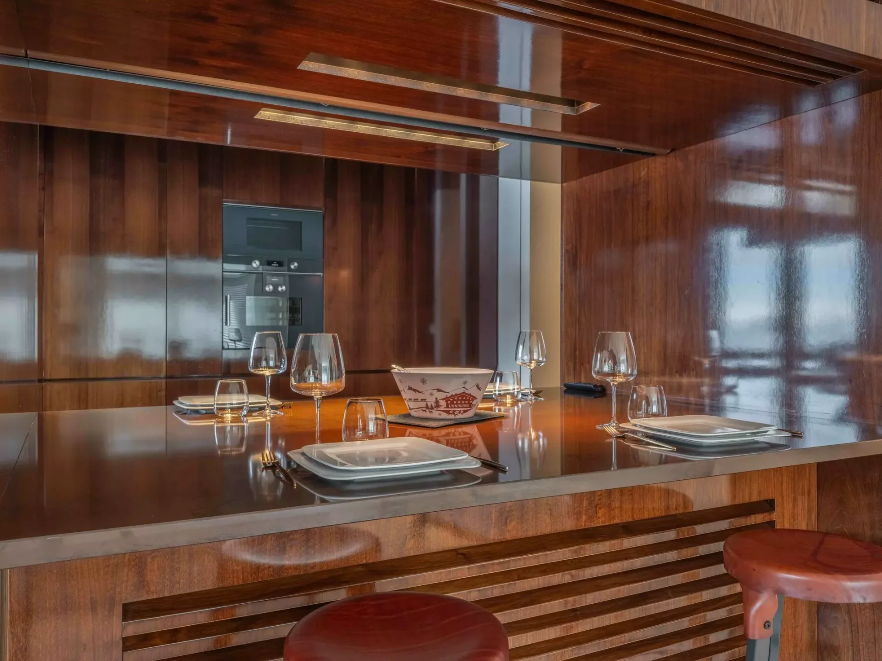 Una barra de comedor pulida está preparada con platos y copas.