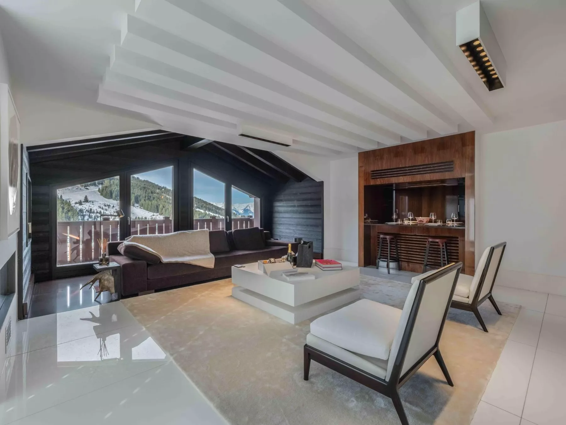 A modern living room has seating around a low table beside large windows.