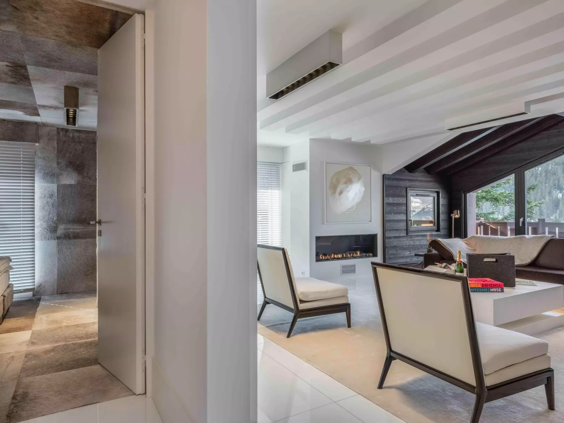 Una sala de estar moderna y luminosa con asientos claros y una pared oscura con chimenea.