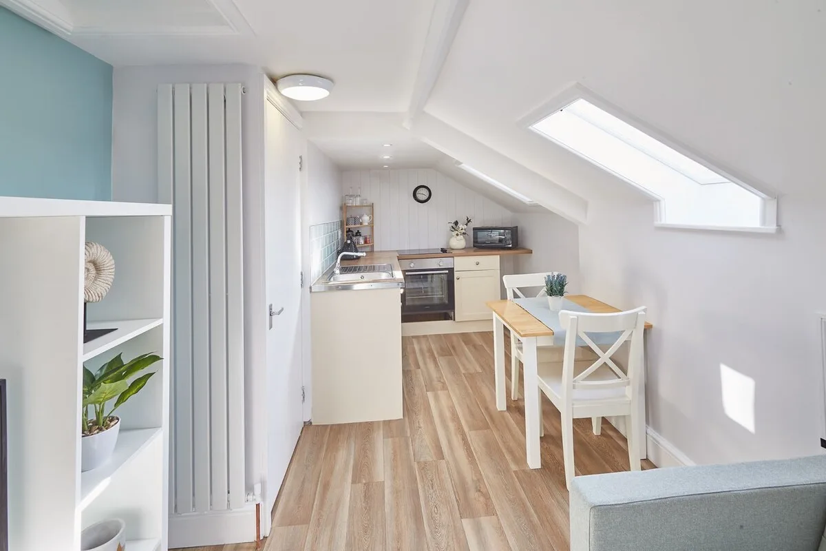 A compact kitchen and dining area with a skylight and light wood flooring.