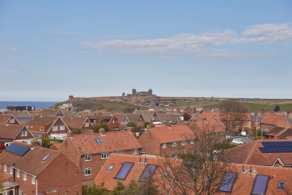 A coastal town with red-roofed houses and a historic castle on the hill.