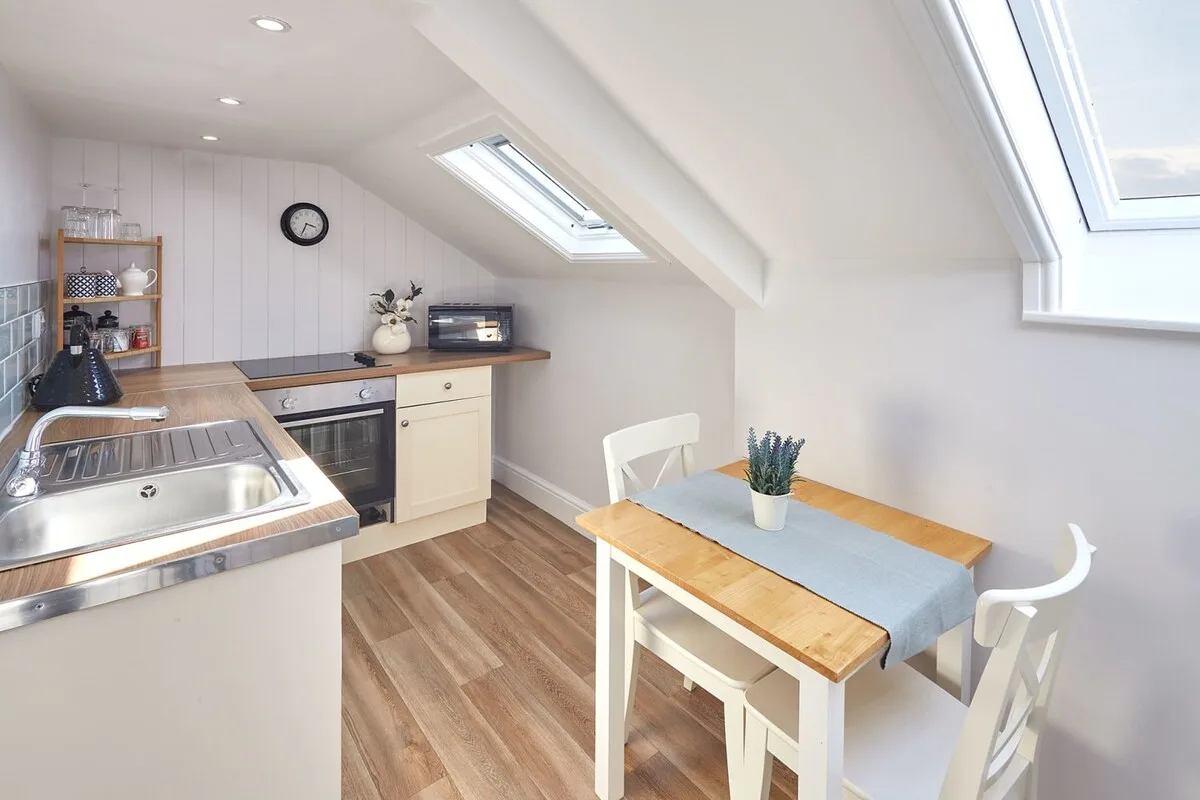 A bright kitchen and dining area with a table beneath sloped skylights.