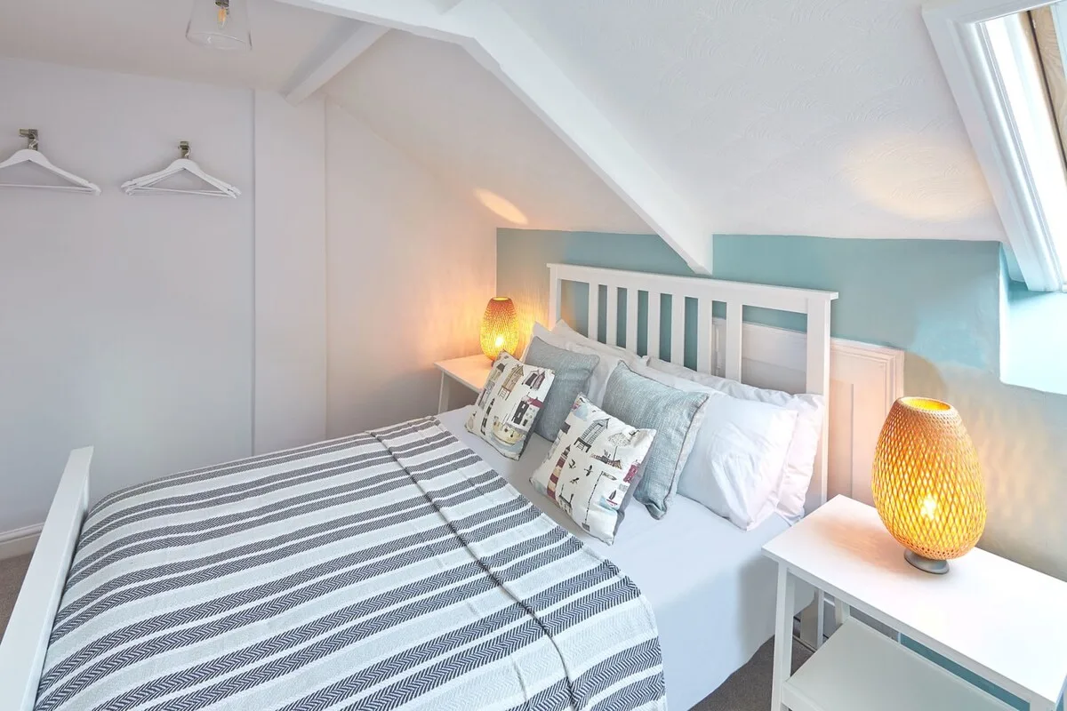 A bright bedroom with a striped bedspread and bedside lamps.
