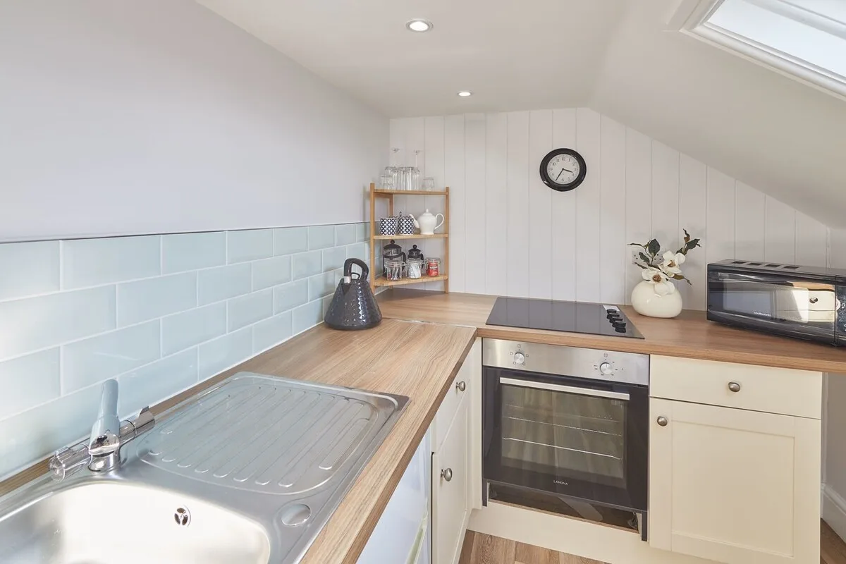 A bright kitchen with a sink, tiled backsplash, and built-in oven.