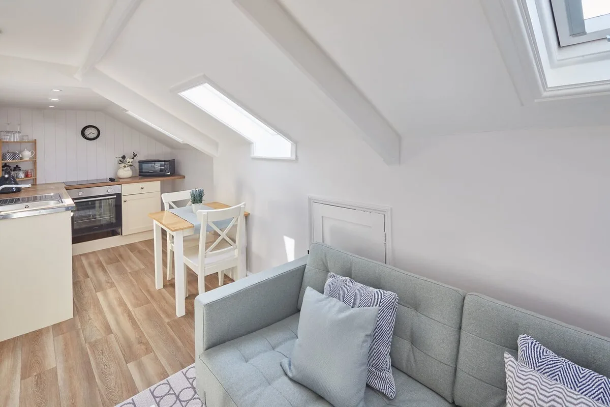 A bright open-plan kitchen and living area with a dining table and seating.
