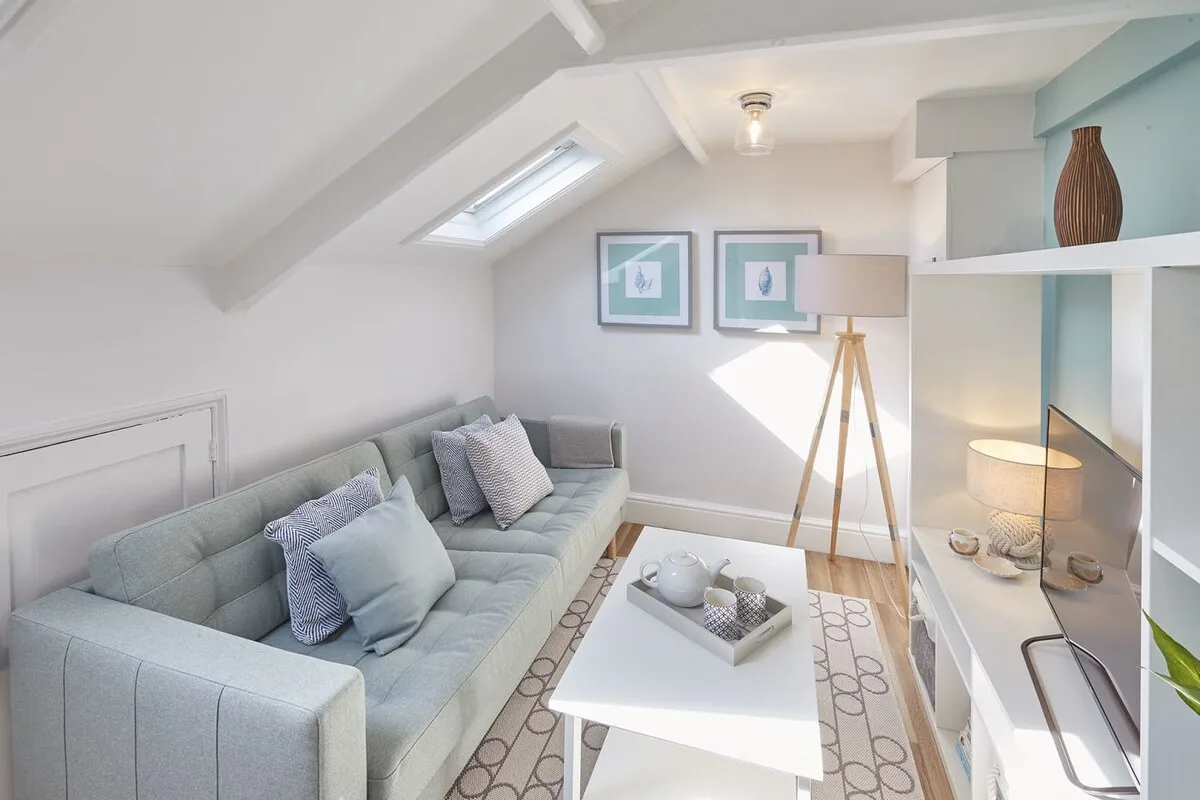 A bright living room with pale seating and a skylight.