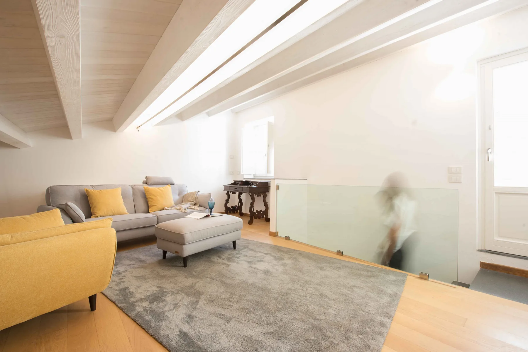 Una sala luminosa con asientos, una alfombra y vigas de techo expuestas.