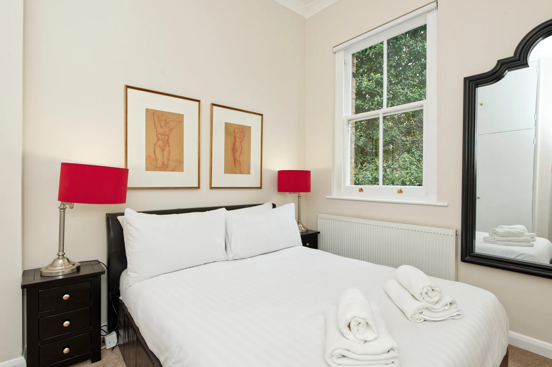 Un dormitorio con una cama bien tendida, lámparas de noche y una ventana.