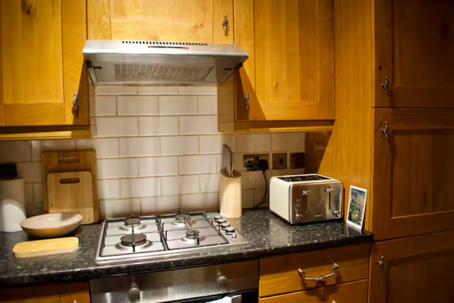 Una encimera de cocina con una placa de gas, una tostadora y armarios de madera.