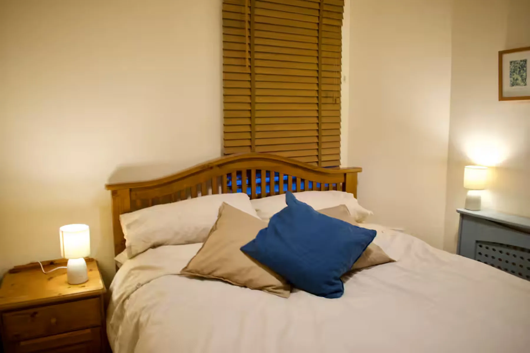 Un dormitorio con una cama de madera y almohadas azules y beige.