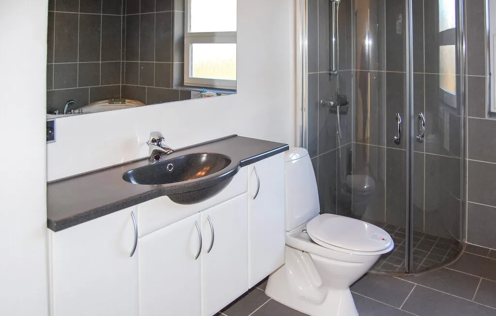 Un baño con lavabo, inodoro y ducha con mampara de vidrio.