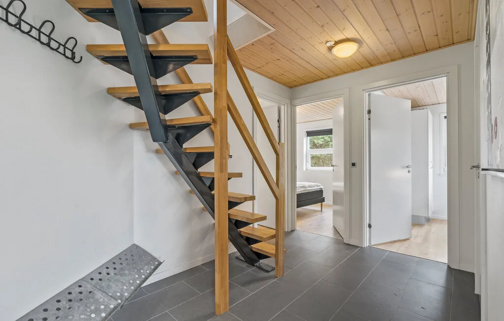 Un pasillo interior con una escalera abierta y puertas que dan a habitaciones contiguas.