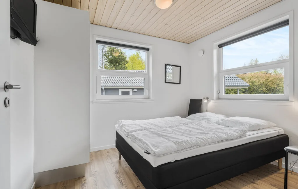 Un dormitorio con una cama bajo dos ventanas.