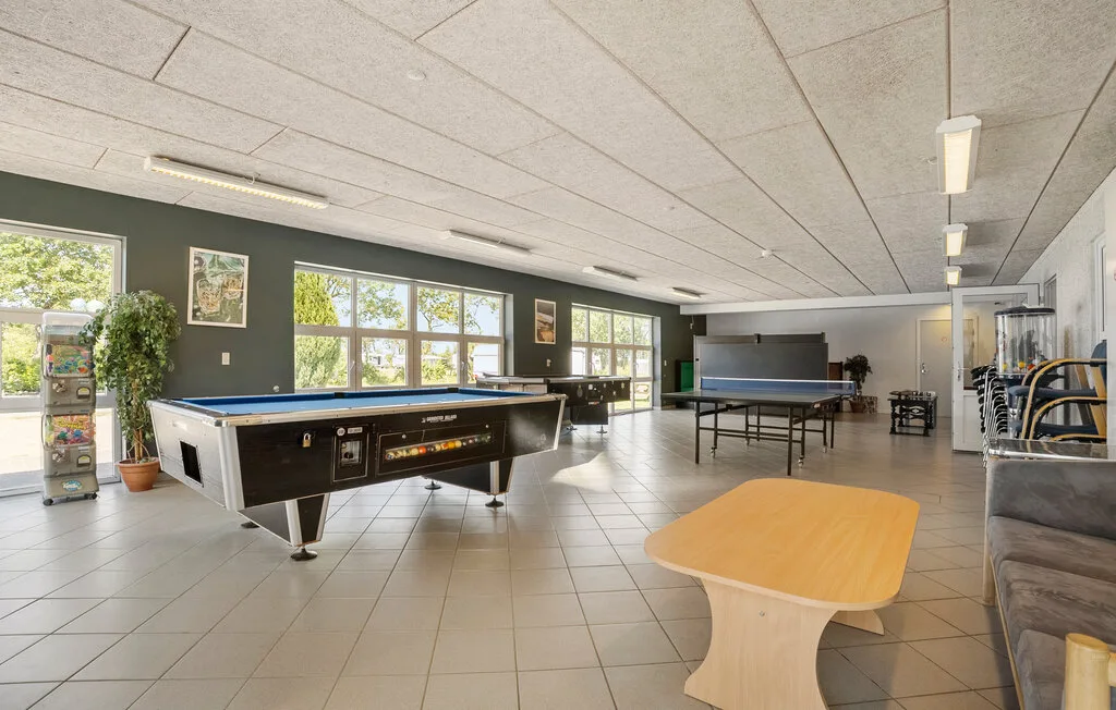 Una sala de recreación con una mesa de billar, una mesa de ping-pong y asientos.