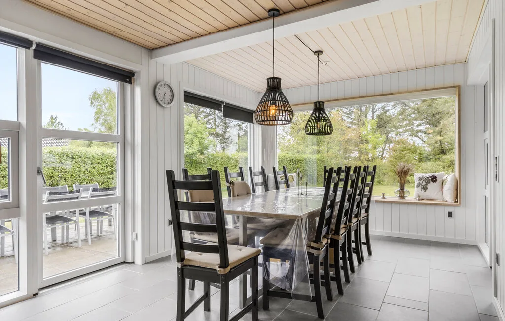 Un comedor luminoso con una mesa larga y grandes ventanas con vistas a la vegetación.