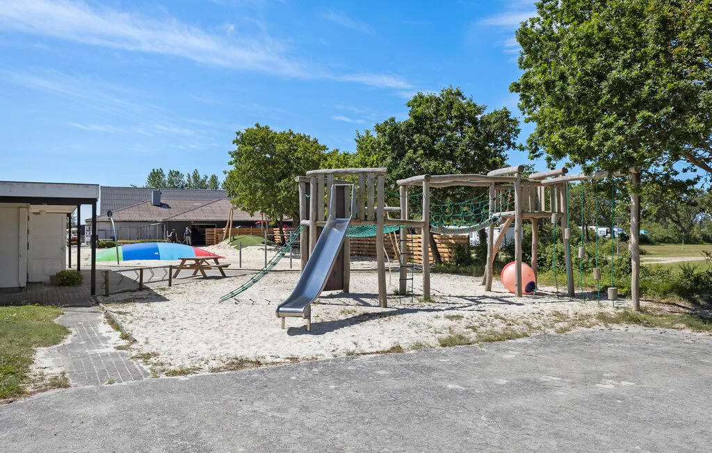 Un parque infantil al aire libre con un tobogán y estructuras para trepar sobre arena.