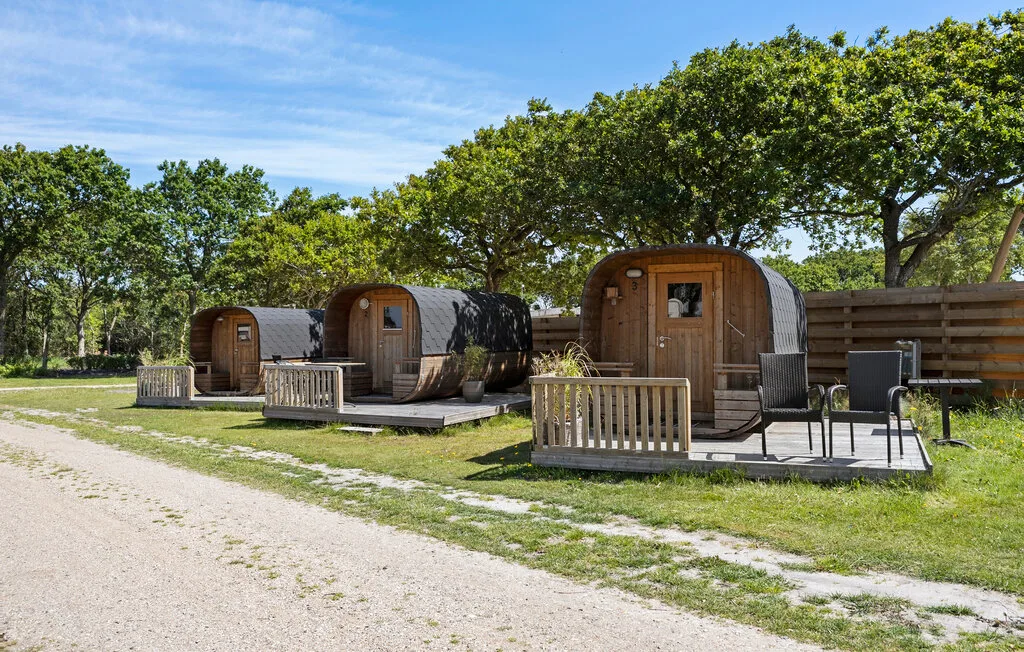 Cabañas al aire libre con pequeños patios cercados junto a un camino de grava.