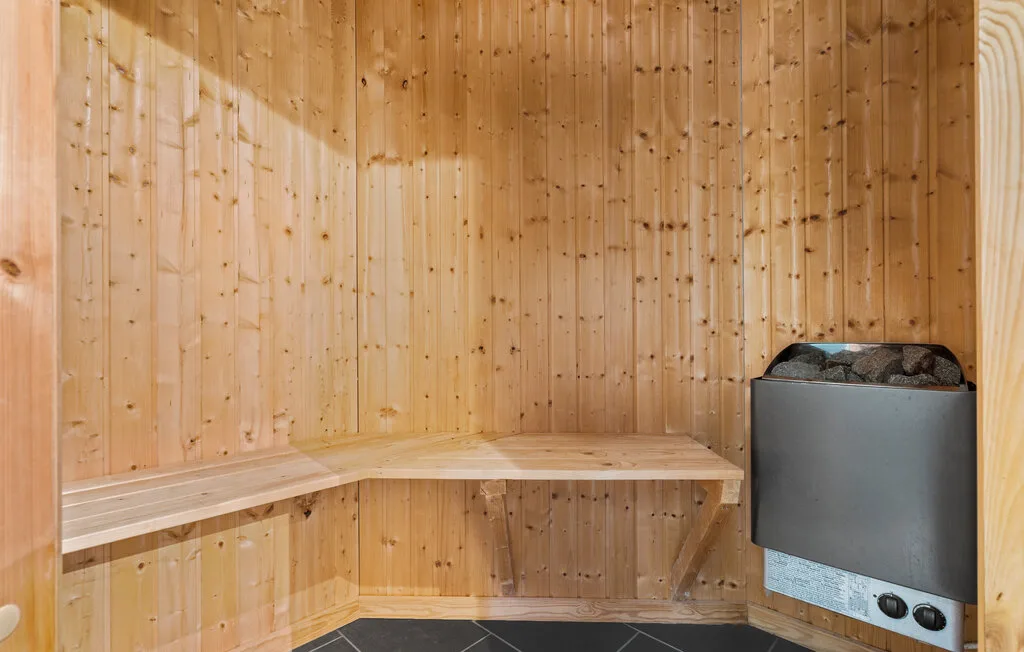 Una sauna revestida de madera con asientos escalonados y un calentador.