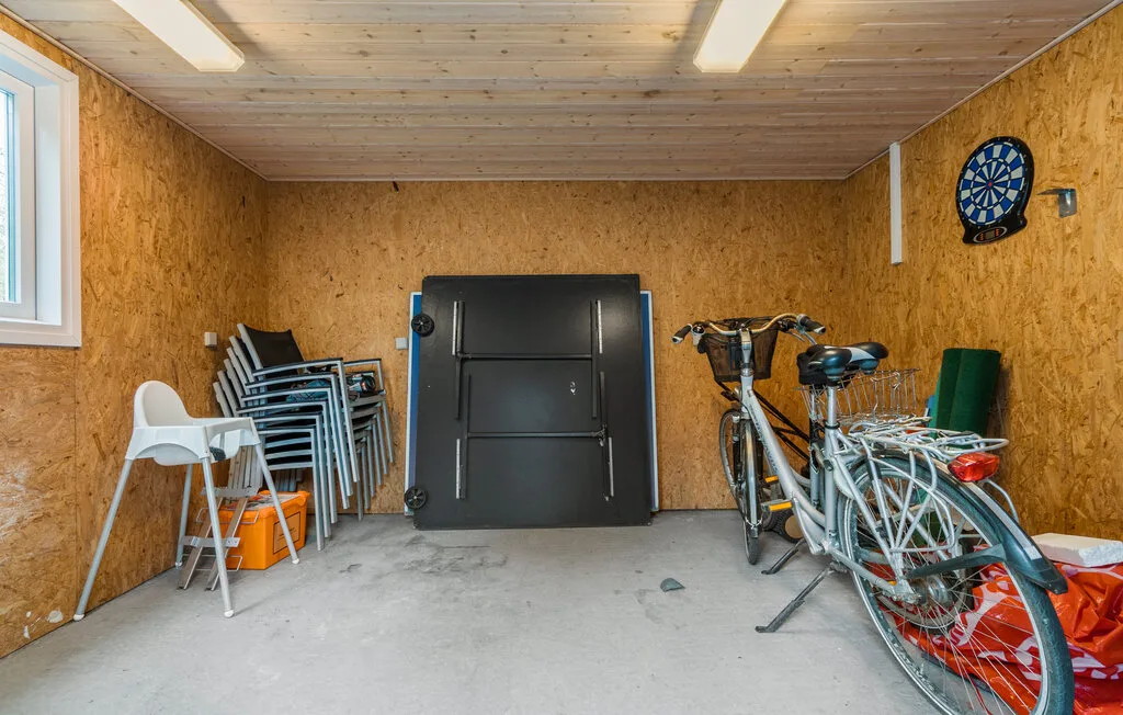 Un cuarto de almacenamiento con sillas apiladas y bicicletas junto a las paredes.