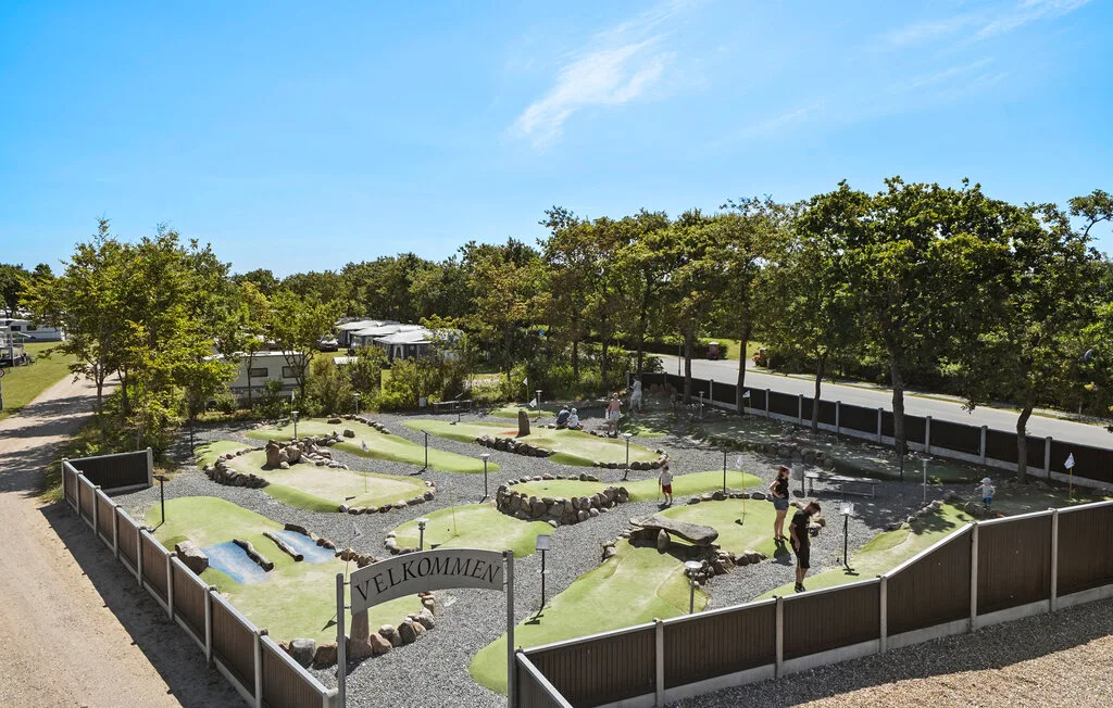Un campo de minigolf al aire libre con greens serpenteantes y árboles.
