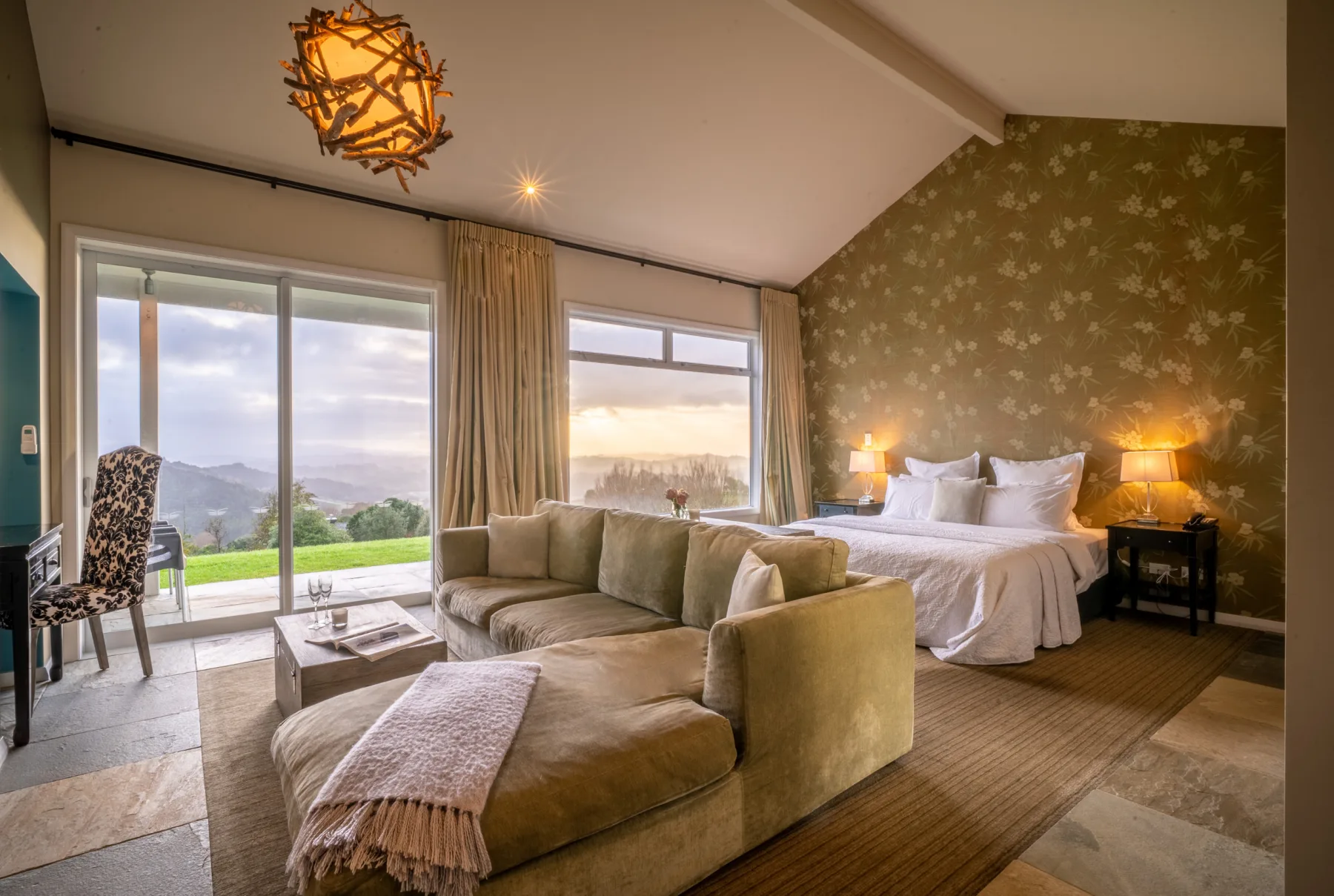 Interior de una villa con cama king, zona de estar y vistas al paisaje rural.