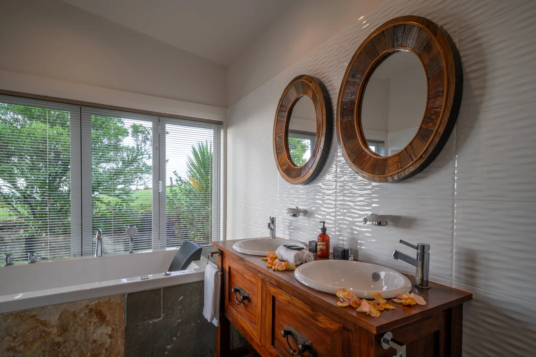 Baño de una villa con dos espejos y detalles de madera.