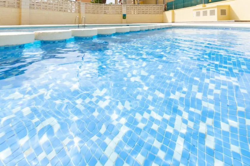 An outdoor swimming pool with blue tiled water.