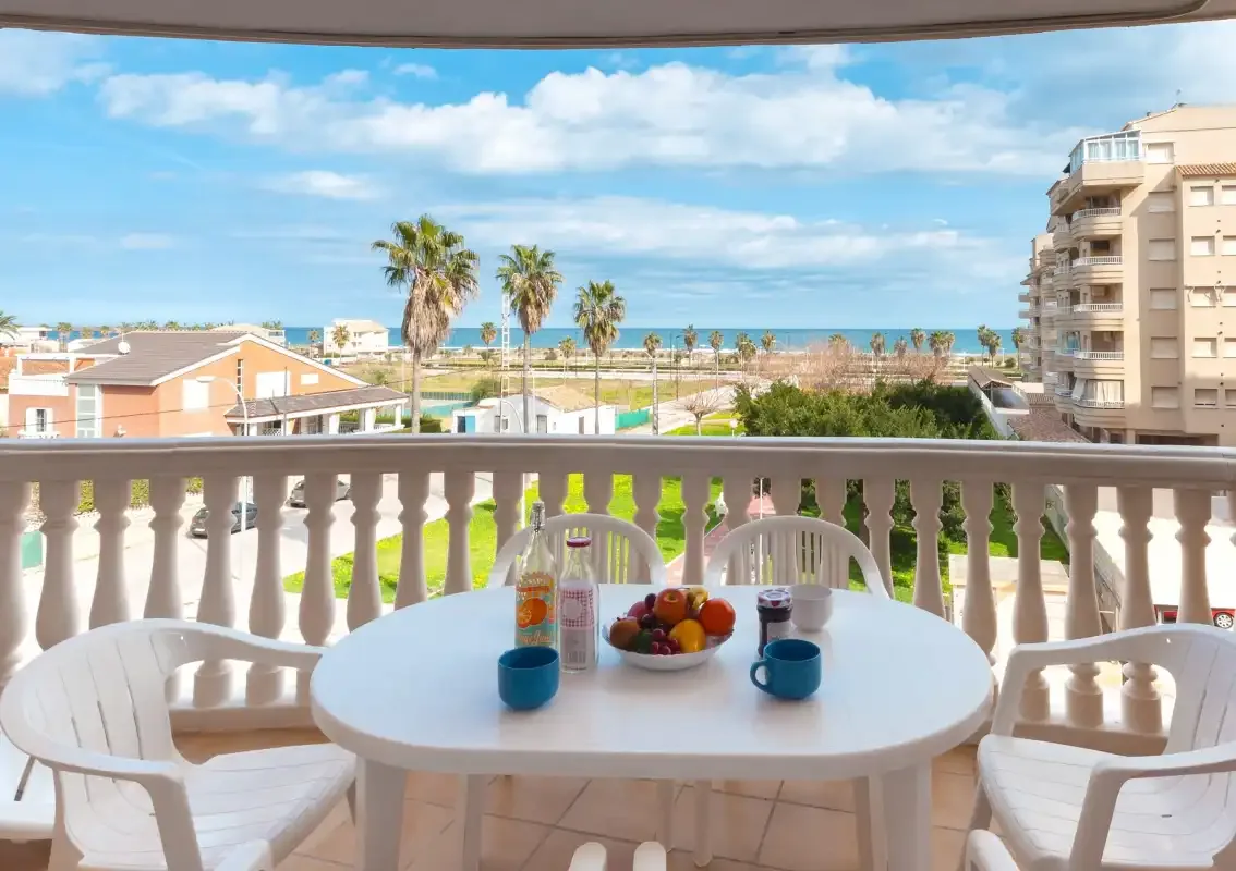 A balcony dining area overlooks palm trees and the sea.
