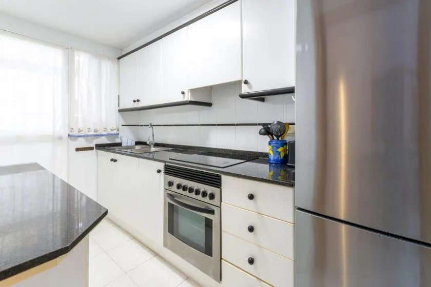 A bright kitchen with white cabinets, a countertop, and an oven.